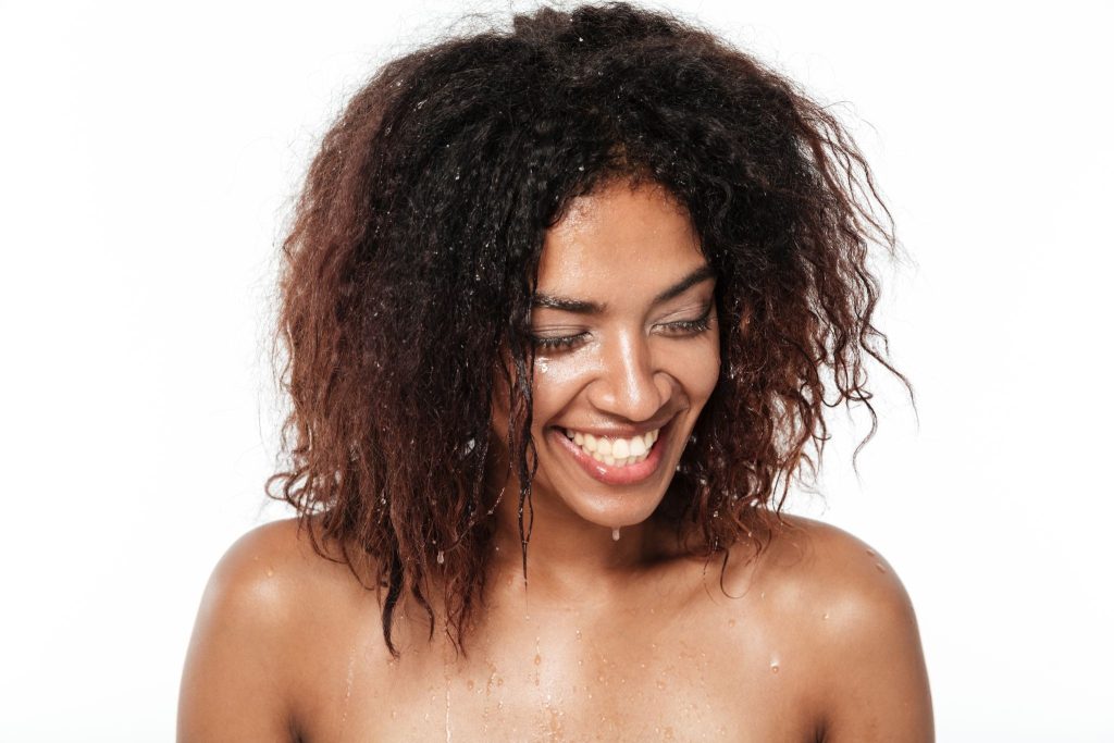 Woman with wet, freshly hydrated curls, showing how water, not oil, moisturizes high-porosity hair, taught at a curly hair salon in Gilbert.