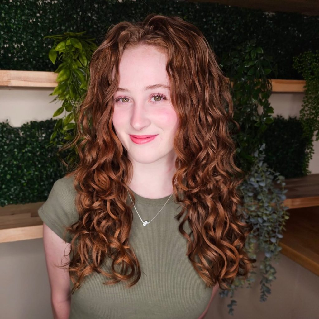Client with long, defined auburn curls styled at Curls Gone Wild Salon, a Gilbert curly hair salon.